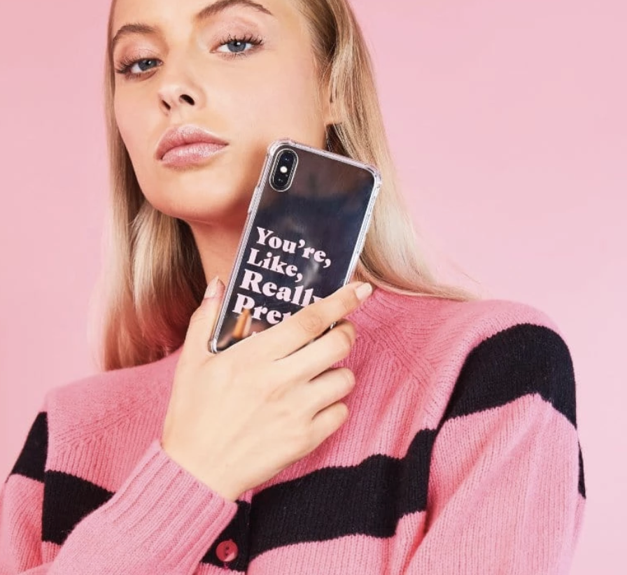 Kvinna håller ett mobilskal med texten "you're, like, really pretty.